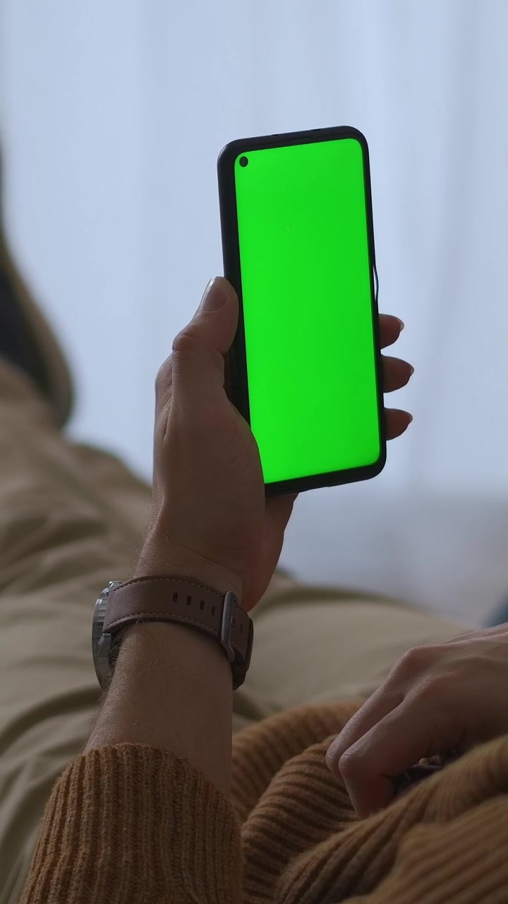 Primo piano della mano di un uomo che tiene uno smartphone con schermo verde