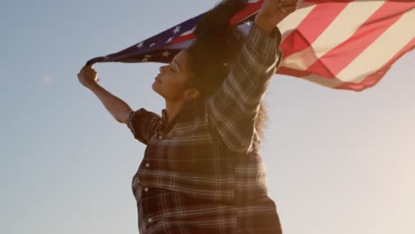 Woman-waving-american-flag-on-the-beach-in-the-sunshine-4k