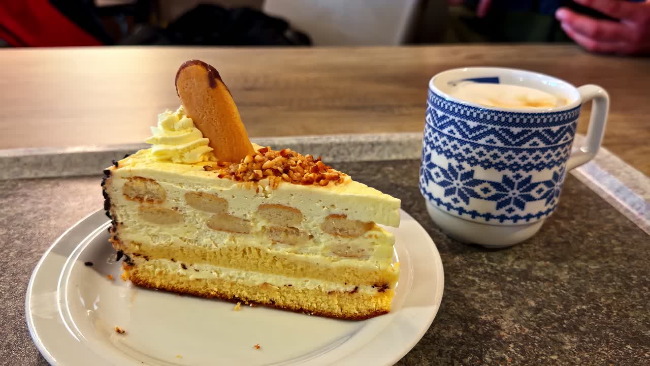 Nauders, Avusturya'da, tepside bir fincan kahve ile servis edilen, kremalı ve bisküvili katmanlı pasta dilimi.