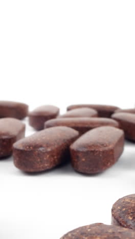 pastillas de suplementos a base de hierbas esparcidas sobre un fondo blanco limpio con un enfoque suave