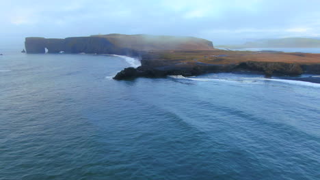 avión no tripulado cinematográfico panorámica impresionante amanecer temprano en invierno en la playa de arena negra apóstoles con fuego de cueva y hielo océano junto a dyhrolaey faro reynisfjara islandia