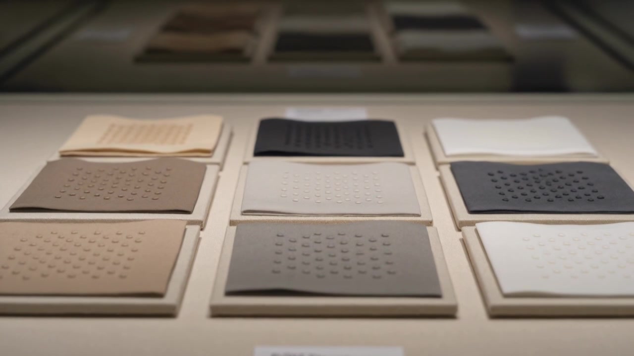 Racking focus camera moving over museum plinth, revealing nine swatches' dotted textures for study