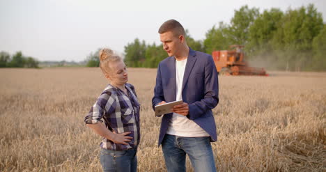 agriculture female and male farmers talking at wheat field during harvesting 13