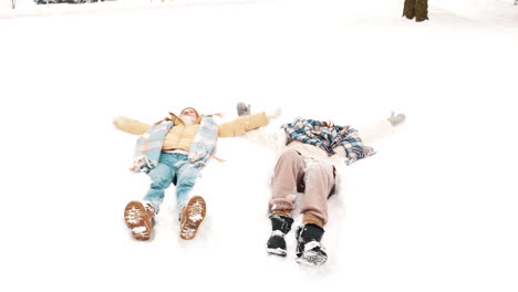 couple making snow angels in a park