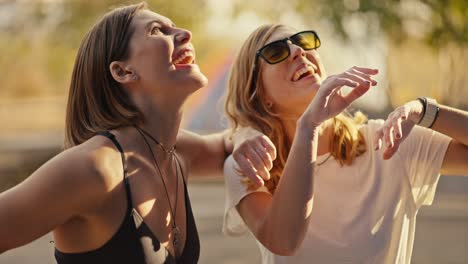 dos amigos escaladores, una chica rubia con gafas de sol y una camiseta blanca y su amiga una chica con un peinado bob, están mirando la ruta en la pared de escalada e imaginando cómo encajan detrás de las repisas para escalar durante su entrenamiento de escalada en roca, se ríen en el verano