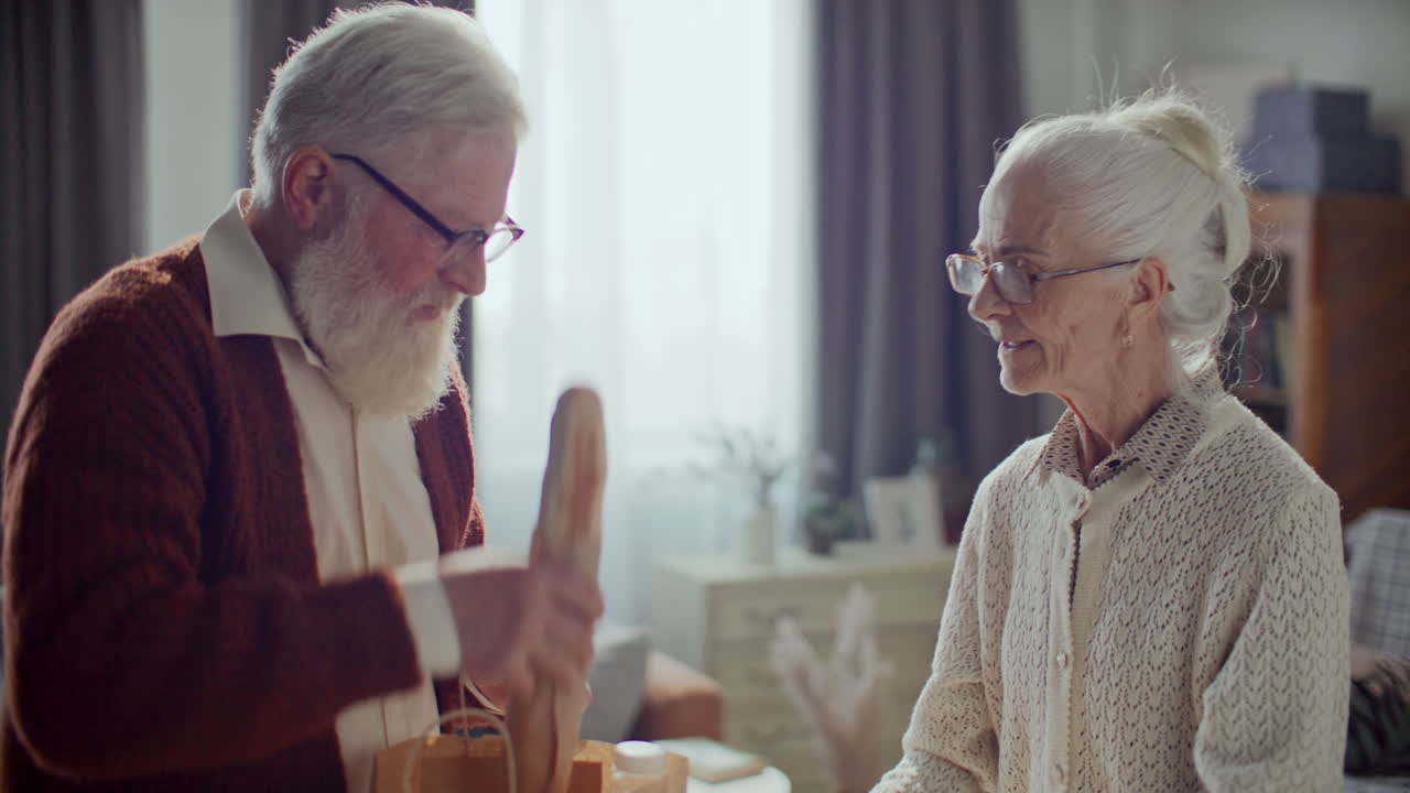 Senior Man Unpacking Groceries at Home with Help from Wife