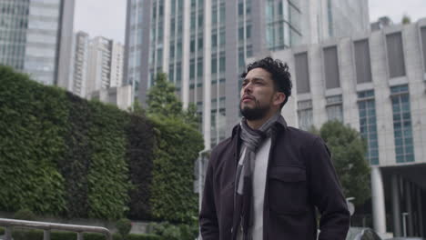 hombre estresado y reflexivo camina solo en el distrito del centro en una tarde nublada gris