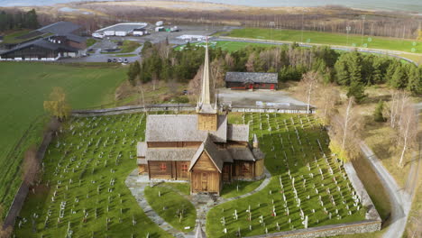 Inclinación-Hacia-Abajo-De-La-Iglesia-De-Madera-De-Lom-Con-Cementerio-En-Prados-Verdes-Durante-La-Tormenta-De-Nieve-En-Noruega