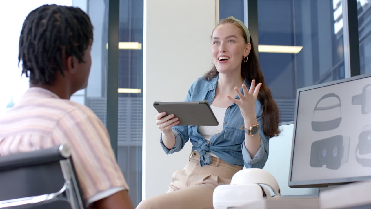 Discussing project details, woman holding tablet and talking to colleague in office