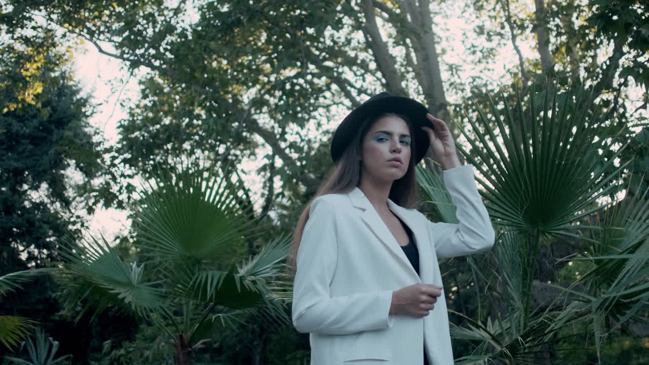 젊은 소녀 모델이 배경에 열대 식물과 함께 포즈를 취하고 있습니다.