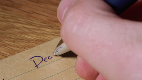 person writing self help letter for goal setting idea on brown lined paper