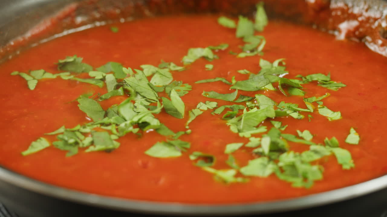 Chicken in tomato sauce is boiling on a frying pan with spices. Cooking tomato sauce curry with chicken fillet. Traditional Italian Mexican Asian dish. High quality studio shot for cafe, restaurant close up.