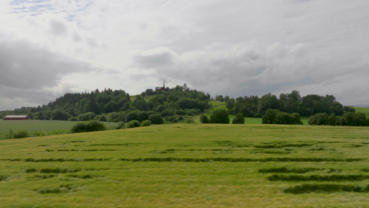 먼 배경의 언덕 꼭대기에 교회가 있는 광대한 농지에 있는 푸른 밀밭