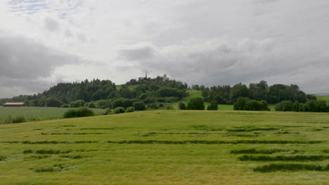 Campos-De-Trigo-Verde-En-Vastas-Tierras-De-Cultivo-Con-Una-Iglesia-En-La-Cima-De-Una-Colina-En-Un-Fondo-Distante