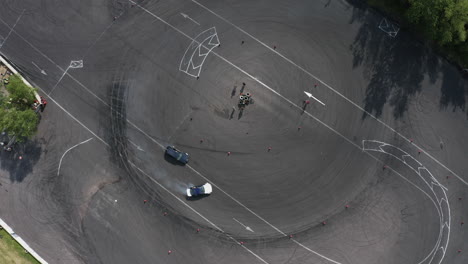 top down aerial shot of two sport cars drifting in circle on asphalt