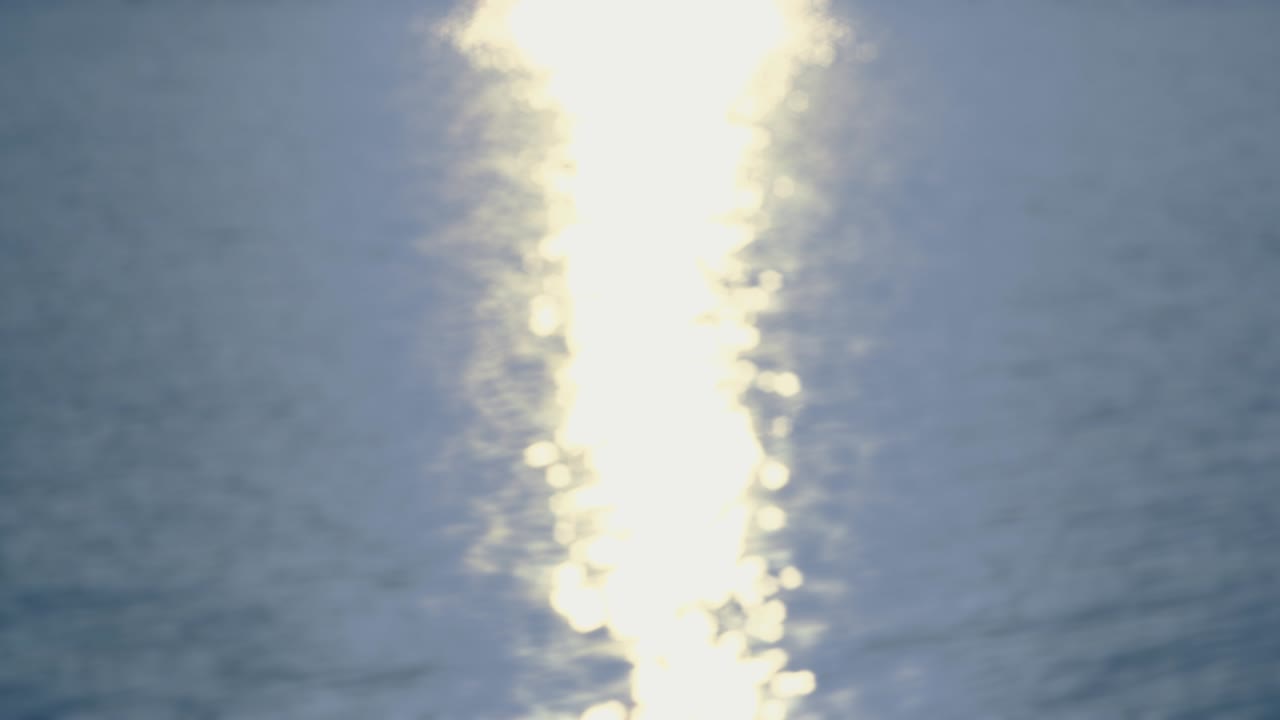 바다 에서 - 반사된 빛의 아름다운 보케와 함께 파도 모양의 물 표면의 완전히 초점을 맞추지 않은 4k 의 완벽한 루프