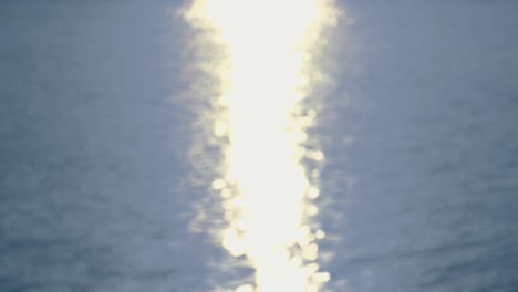 por el mar - bucle sin costuras de una toma de 4k completamente desfocada de una superficie de agua ondulada con un hermoso bokeh de luz reflejada
