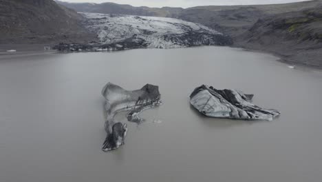 vista aérea sobre bloques de hielo en la laguna glaciar solheimajokull - inclinación, disparo de drones