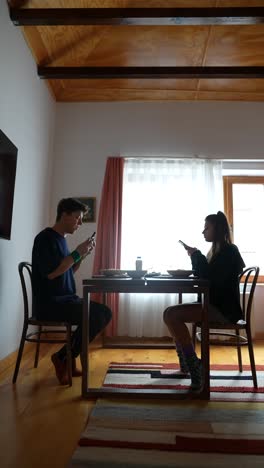 pareja comiendo mientras usan sus teléfonos