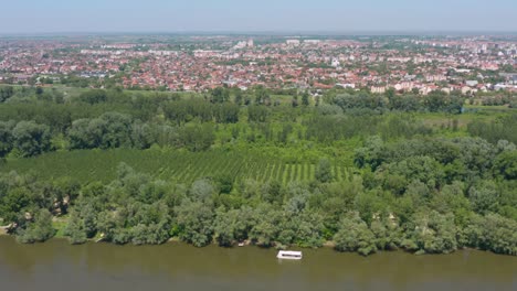 Beautiful-drone-shot-of-the-riverside-of-the-Danube-River-with-a-Serbian-city-behind