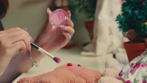 applying blush to a teddy bear
