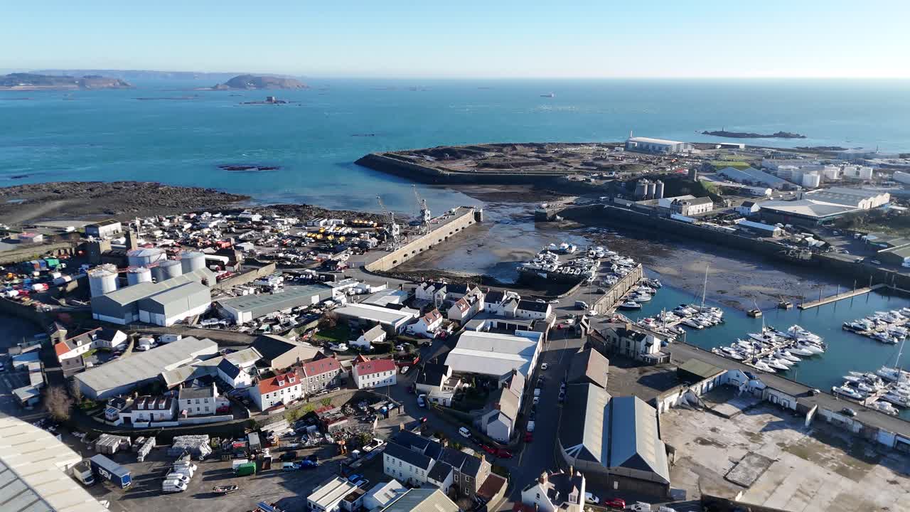 Guernsey St Sampsons harbour.Overhead drone then reveal of harbour entrance and marina rising over industrial zone with final views of Herm and Jethou in late afternoon sun