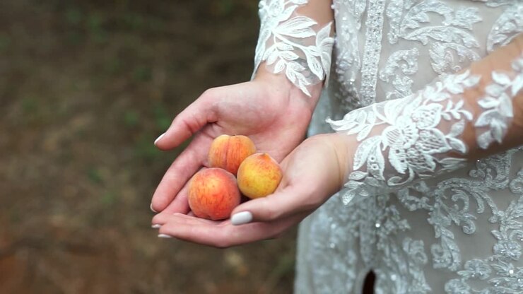 Primo piano di sposa che tiene delle pesche