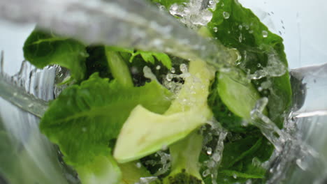 closeup water pouring blender with vegetables fruits herbs in super slow motion.