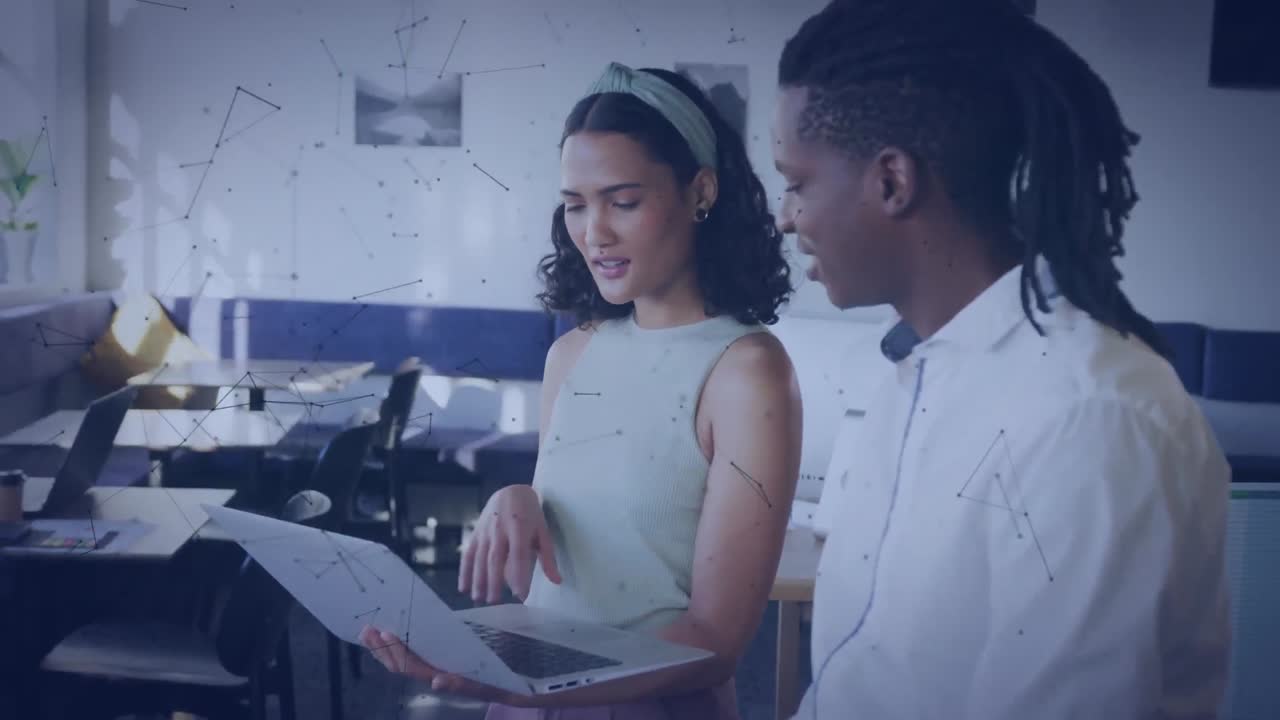 Animation of connected dots over diverse coworkers discussing report on laptop at office