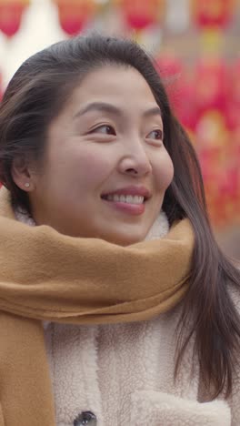 vertical video portrait of smiling young asian woman visiting chinatown in london uk