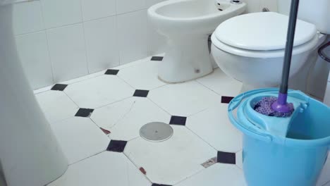 medium shot of mop squeezing inside bucket with wringer inside restroom