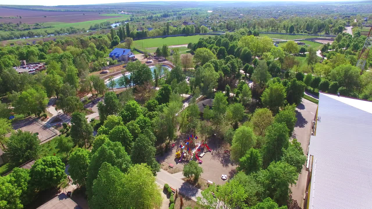 Beautiful green city park with artificial pond in the middle. Acres of greenery and walking paths from birds' eye view.