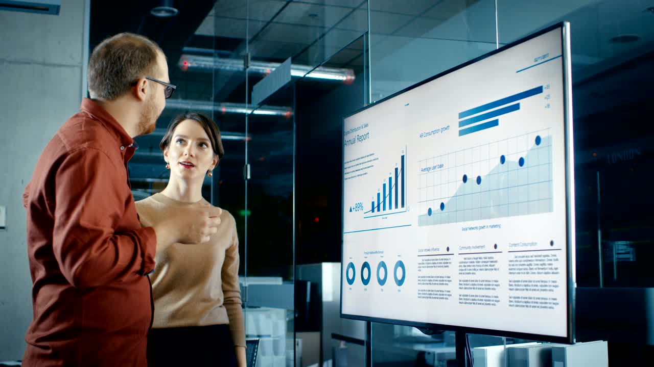 compañeros de trabajo de negocios masculinos y femeninos en la sala de conferencias tienen una discusión sobre estadísticas y gráficos mostrados en una presentación de televisión.
