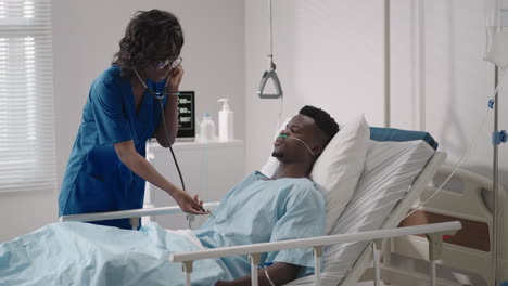 a girl doctor examines and talks to a patient lying on a hospital bed