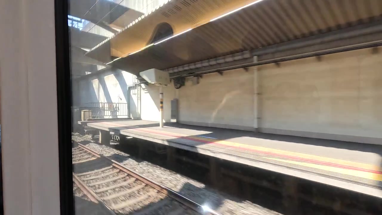 Point of view shot through a train window departing a sunny platform in Tokyo, Japan.