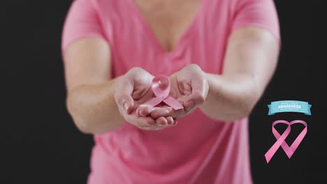 Breast-cancer-awareness-text-banner-against-mid-section-of-woman-holding-a-pink-ribbon