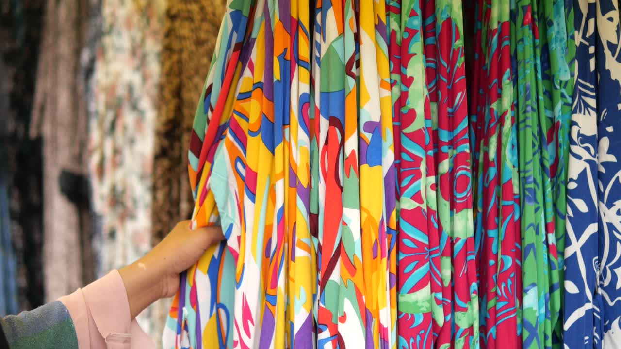 mujer navegando por la exhibición de telas coloridas en la tienda
