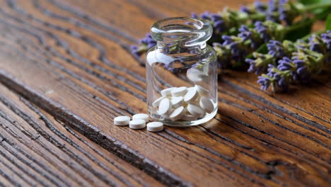 white pills in glass bottle with lavender