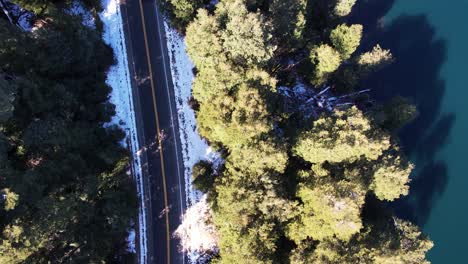 Countryside-road-near-lake-water-in-winter-season,-aerial-top-down-view