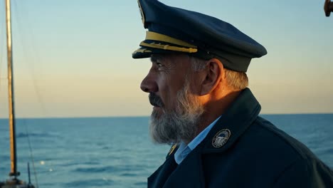 captain of a ship looks out at the ocean during sunset