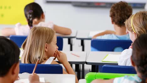 schoolgirl whispering into her friend s ear in classroom