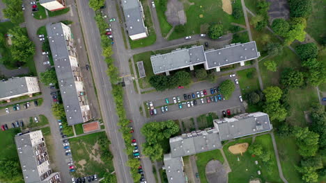 Birds-eye-view-of-a-neighborhood-with-flats,-parks-and-cars-driving-on-the-road