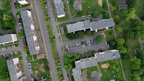 vista de pájaro de un barrio con pisos, parques y coches conduciendo por la carretera