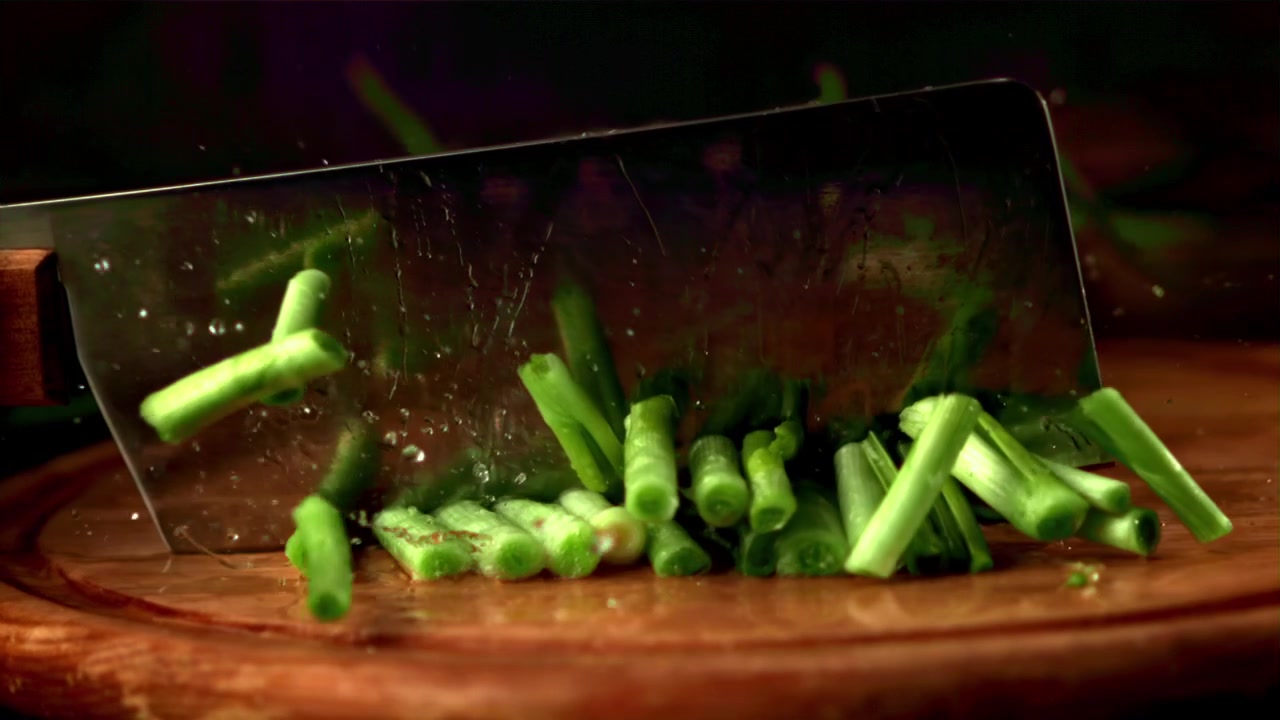 Fresh Green Onions Being Chopped by a Cleaver in Slow Motion