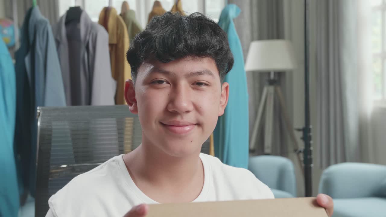 Close Up Of Asian Man Online Seller With Package Look At Camera And Smile While Selling Clothes At Home
