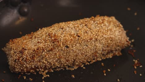 fresh salmon fillet covered in white sesame, pan frying with brown crust, cooking preparation for tataki salmon dish, authentic japanese cuisine, close up shot