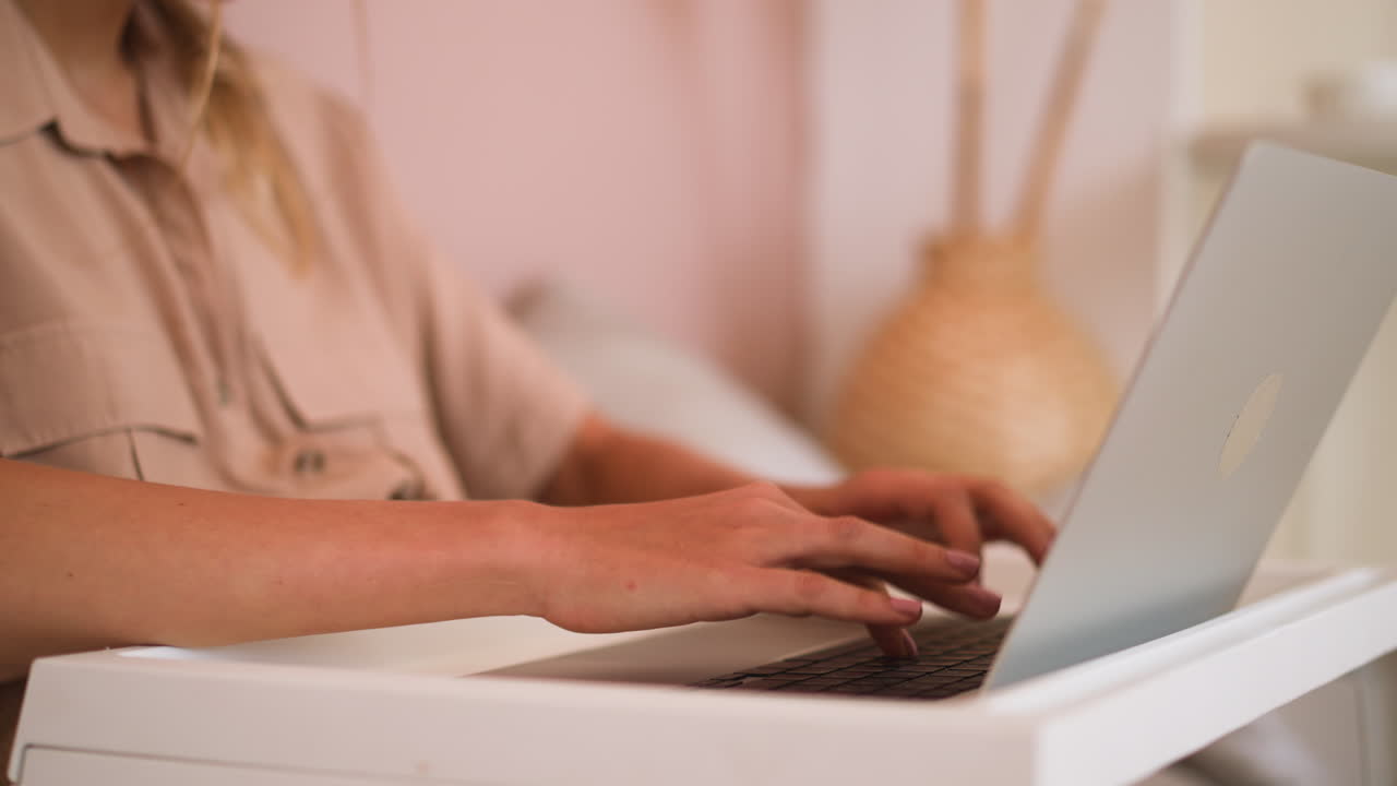 mujer escribe un mensaje en el teclado de una computadora portátil moderna en la cama