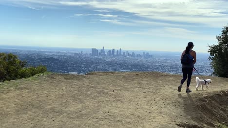 female hiking with dog scenic viewpoint overlooking hazy downtown los angeles city skyline