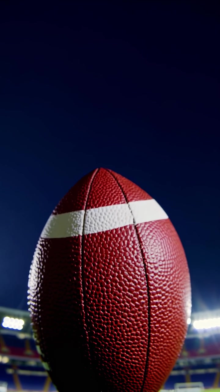 American Football Ball Resting on Stadium Grass at Night