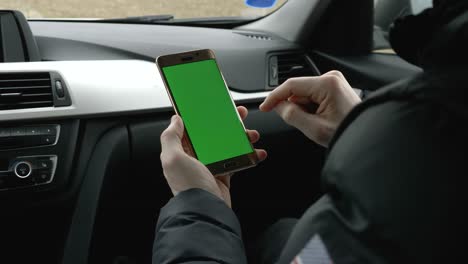 hombre de pantalla verde sosteniendo su teléfono inteligente en un coche